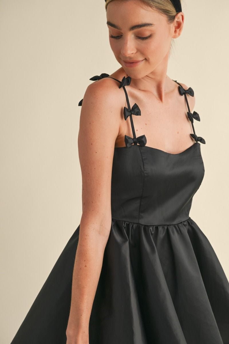 Adjustable spaghetti strap with bow applique detail fit and flare mini dress. Lining. Back invisible zipper