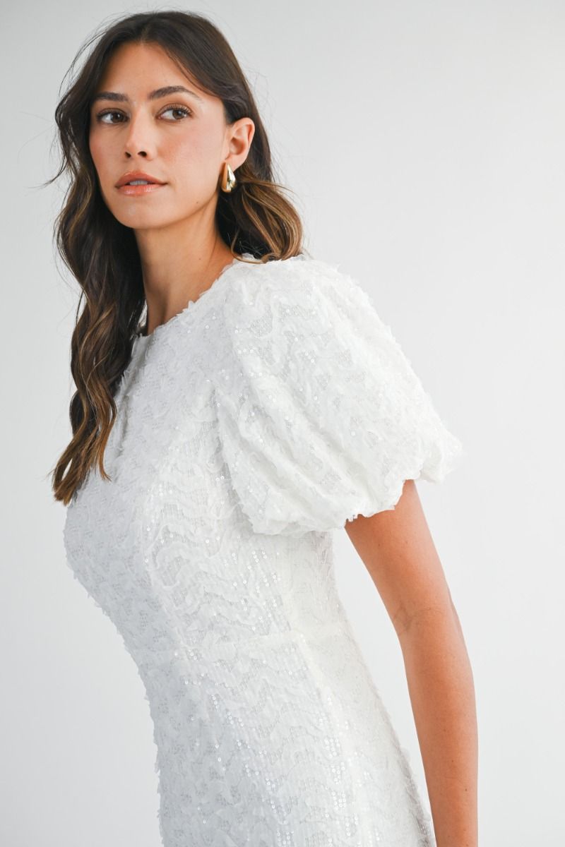 Sequin embellished mesh puff short sleeve fitted midi dress with back slit detail. Back keyhole button closure and invisible zipper